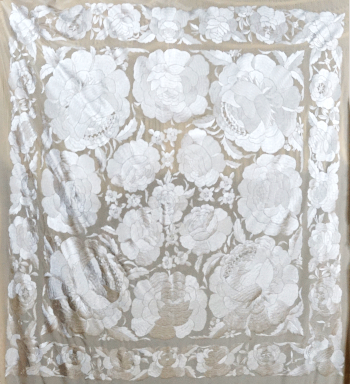 Mantón de seda natural bordado a mano. Diseño de 135 × 135 cm en tono crema con bordado al tono. Pura delicadeza, ideal para ceremonias o estilismos suaves y refinados.