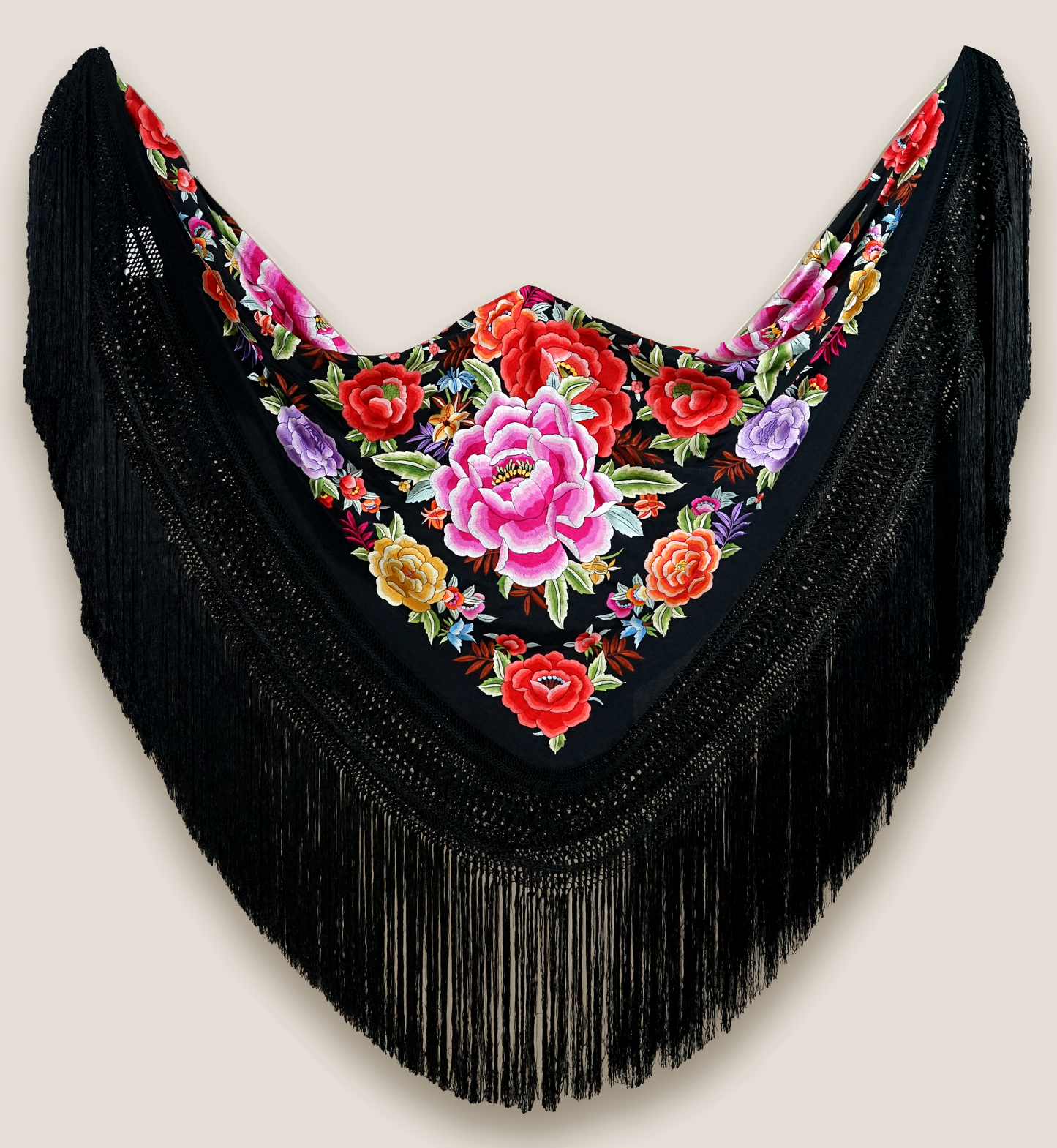 Mantón de seda natural bordado a mano. Bordado multicolor sobre fondo negro en formato 135 × 135 cm. Tradición vibrante con nombre propio.