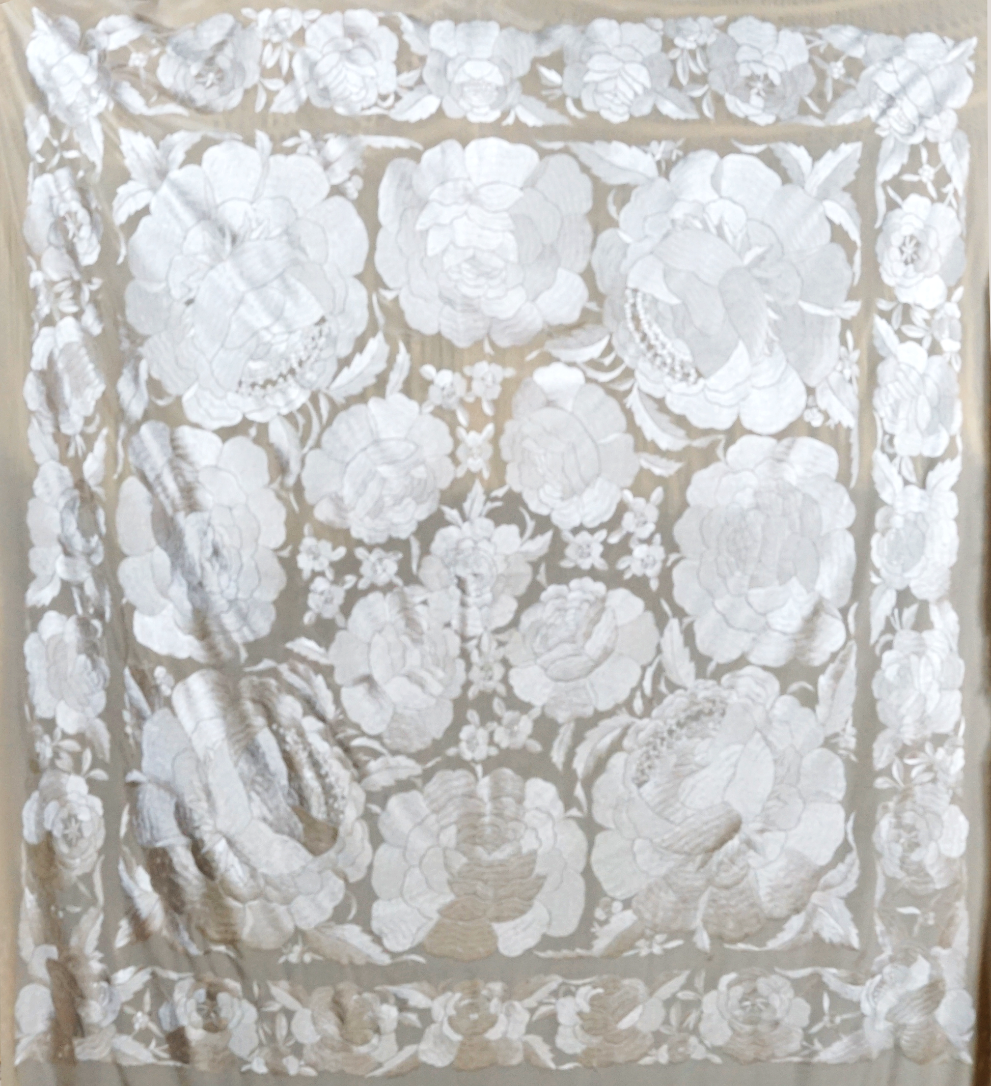 Mantón de seda natural bordado a mano. Diseño de 135 × 135 cm en tono crema con bordado al tono. Pura delicadeza, ideal para ceremonias o estilismos suaves y refinados.