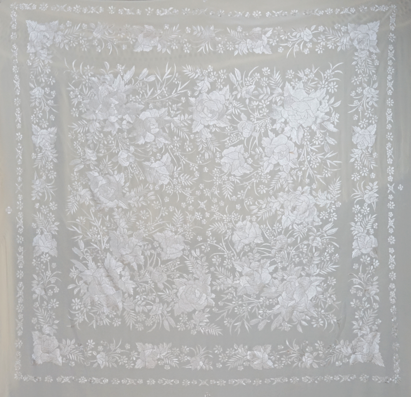 Mantón de seda natural bordado a mano. Pieza en seda color crema con bordado al tono. 135 × 135 cm de delicadeza y elegancia atemporal.