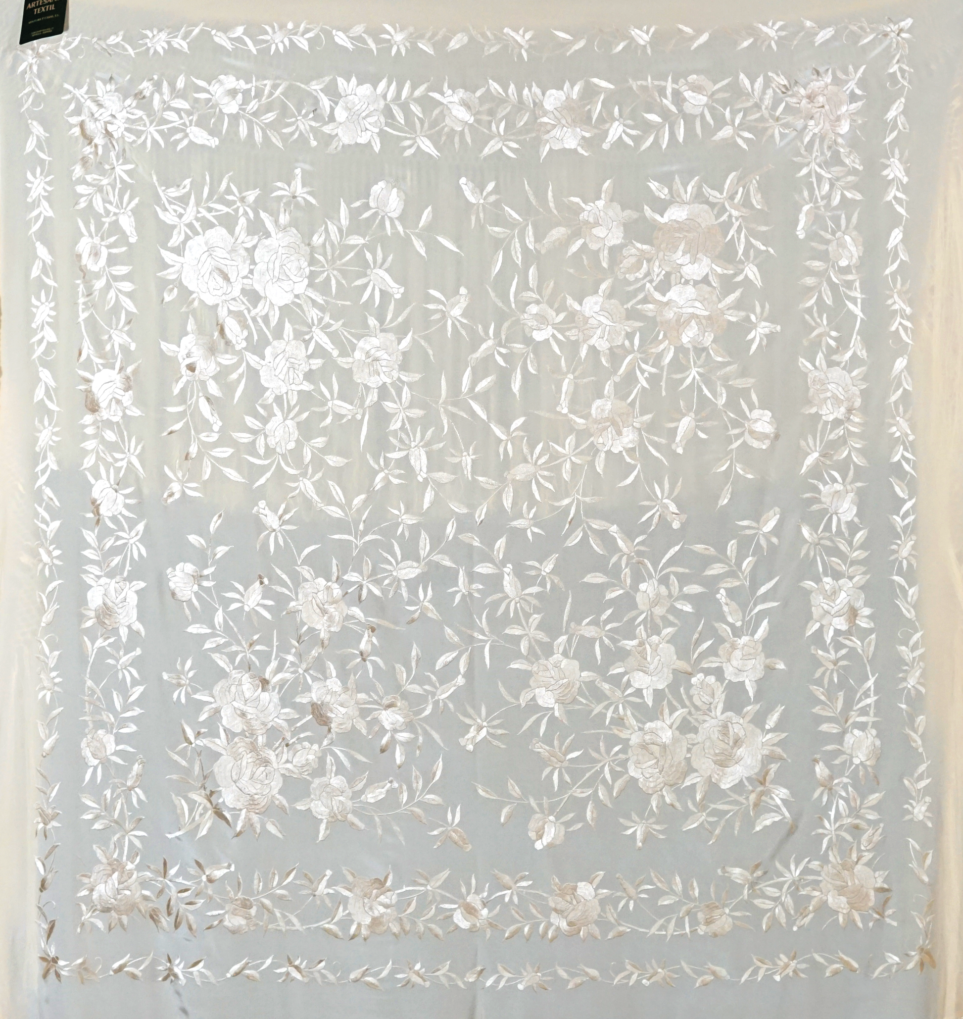 Mantón de seda natural bordado a mano. Pieza armoniosa en tono crema, bordado al tono. 135 × 135 cm. Elegancia sobria para ocasiones especiales.