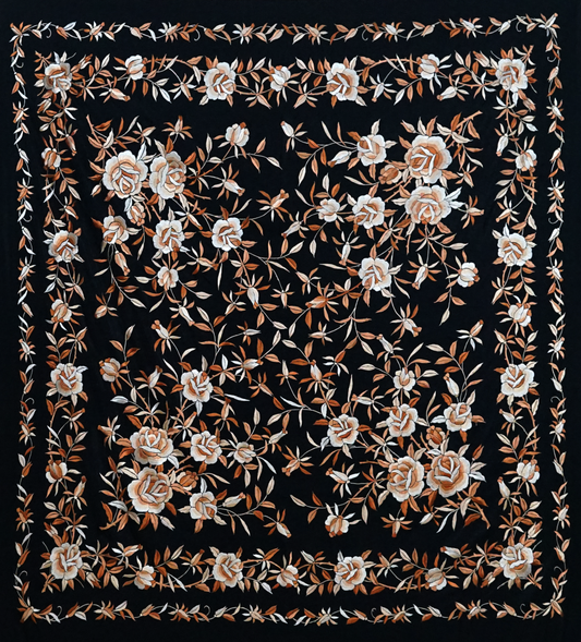 Mantón de seda natural bordado a mano. Diseño sobrio de 135 × 135 cm con fondo negro y bordado en tono crema rebajado. Elegancia serena y artesanal.