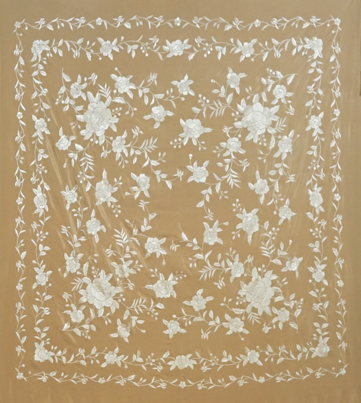 Mantón de seda natural bordado a mano. Pieza en seda tostada con bordado al tono. Formato 135 × 135 cm. Armonía neutra con identidad.