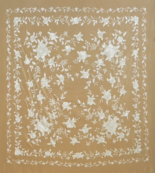Mantón de seda natural bordado a mano. Pieza en seda tostada con bordado al tono. Formato 135 × 135 cm. Armonía neutra con identidad.