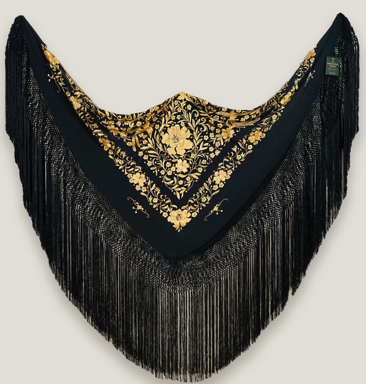 Mantón de seda natural bordado a mano. Pieza de 135 × 135 cm. Fondo negro con bordado en mostaza. Sofisticación cálida y moderna.