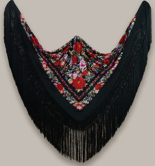 Mantón de seda natural bordado a mano. Diseño clásico de 150 × 150 cm. Seda negra con bordado multicolor que aporta movimiento y expresividad a una pieza de gran elegancia.